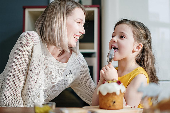 Mother looking at daughter eating her cake